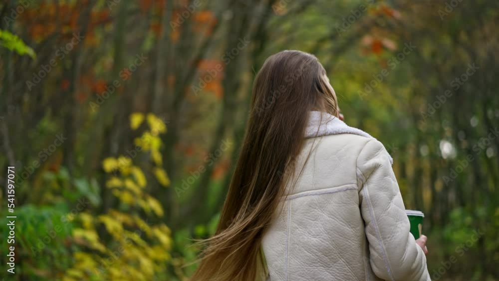 Caucasian lady walking in the nature turns around waving her beautiful long hair. Blurred natural autumn backdrop. Caucasian lady walking in the nature turns around waving her beautiful long hair. Blurred natural autumn backdrop.