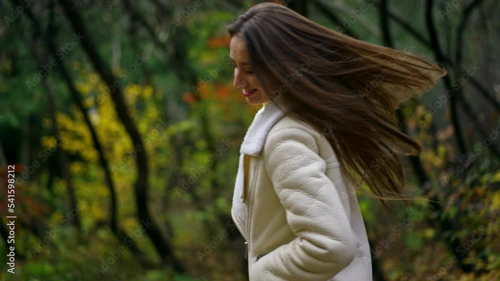 Cheerful happy long-haired lady having fun in the autumn park. Lady in white jacket turns in front of camera showing her beautiful hair. Cheerful happy long-haired lady having fun in the autumn park. Lady in white jacket turns in front of camera showing her beautiful hair.