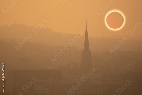 total solar eclipse in early foggy morning on sleeping city