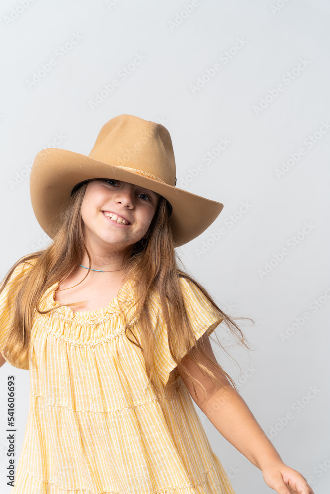 Stylish young girl in yellow dress and orang hat