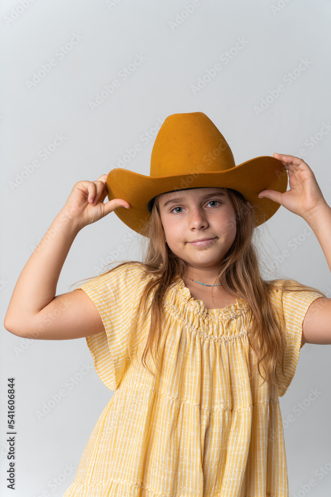 Stylish young girl in yellow dress and orang hat
