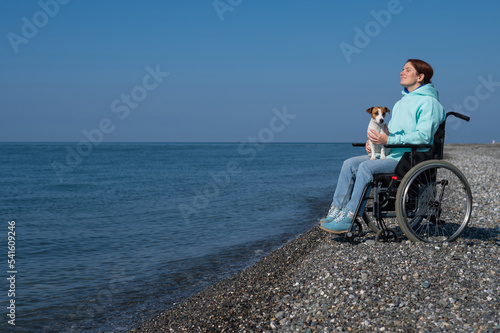 Caucasian woman in a wheelchair with a dog at the sea.