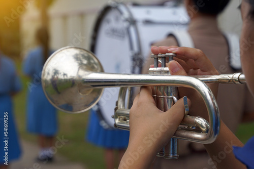 Close-up of student's hand pressing the button of a trumpet to chase a musical note, playing a song while practicing for a school parade. Soft and selective focus. 