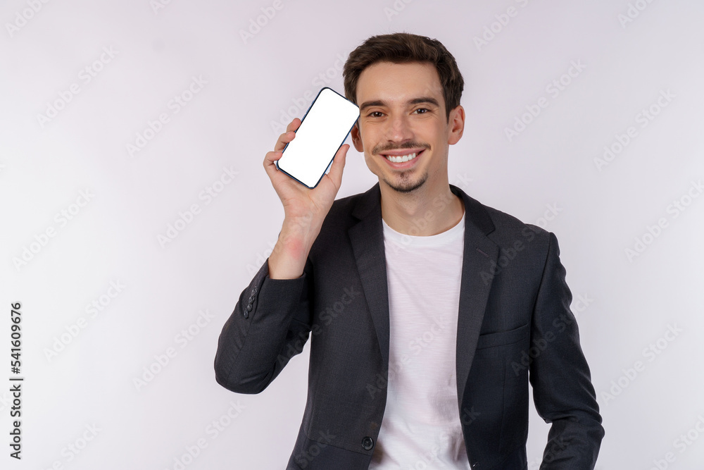 Portrait of young businessman holding smartphone cellphone blank screen with mockup copy space isolated white background Portrait of young businessman holding smartphone cellphone blank screen with mockup copy space isolated white background