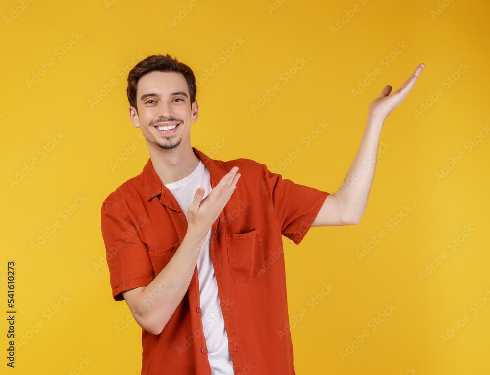 Portrait of happy smiling young man presenting and showing your text or product isolated on yellow background Portrait of happy smiling young man presenting and showing your text or product isolated on yellow background