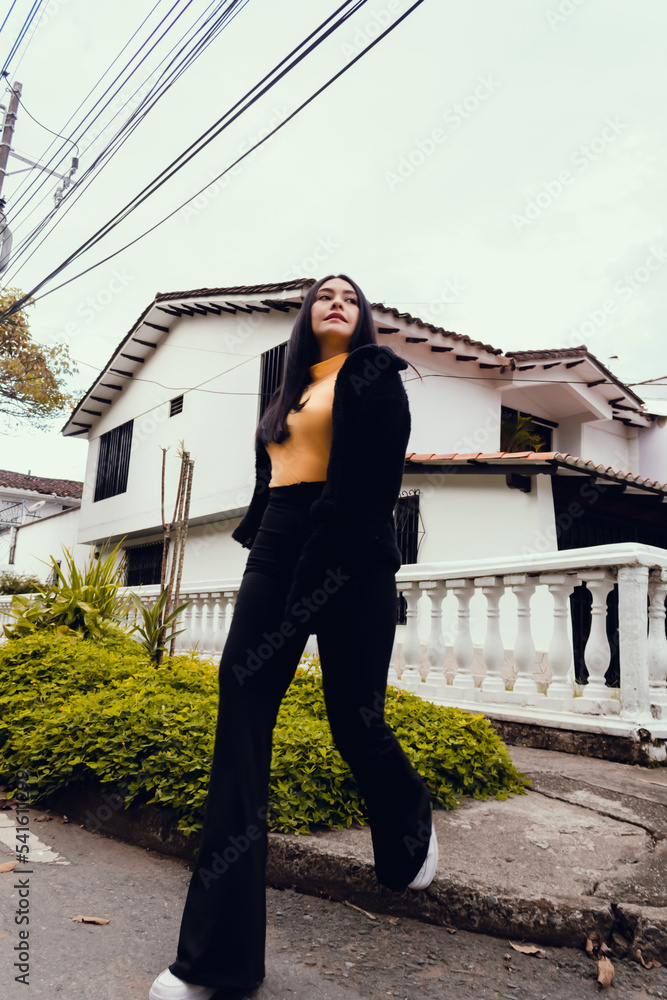 beautiful woman walking on city street wearing fashionable black suit with orange blouse outdoors. beautiful woman walking on city street wearing fashionable black suit with orange blouse outdoors.