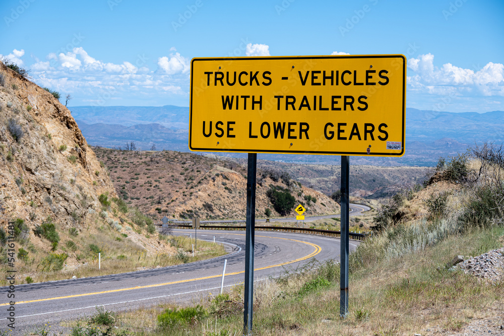 A cautionary sign for trucks and vehicles with trailers to use lower gears while driving down hill