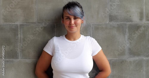 Portrait of beautiful body positive girl with colored hair. She looks straight into the camera and smiles at the end of the clip, and we see orthodontic braces on her teeth.