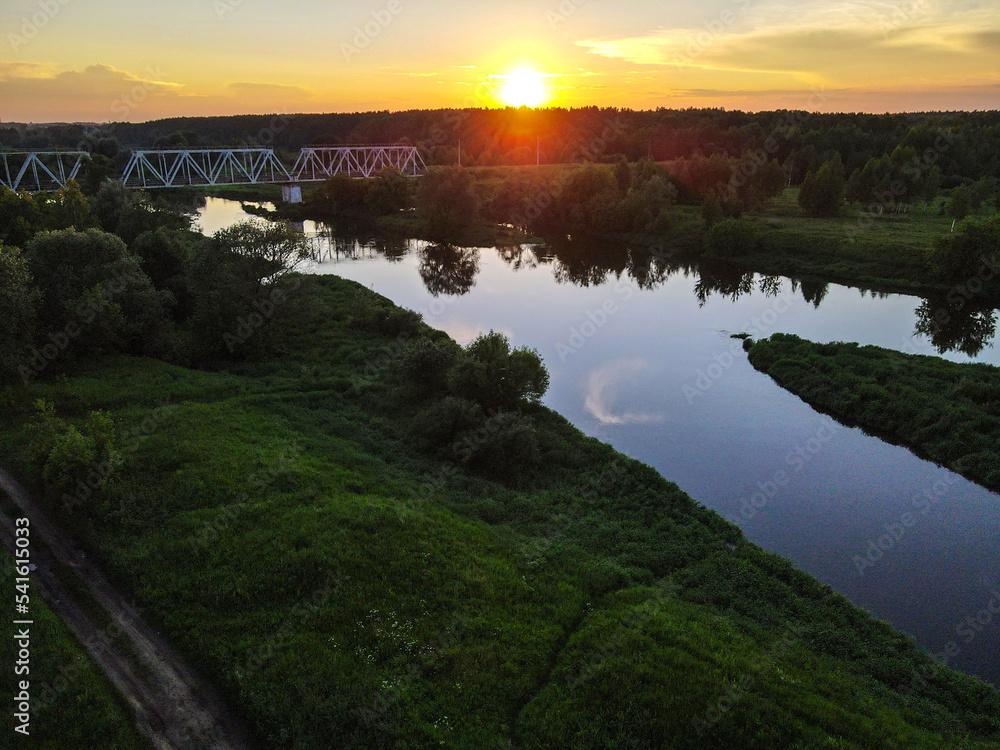 Landscape with a railway bridge over the Klyazma river on the background of sunset.