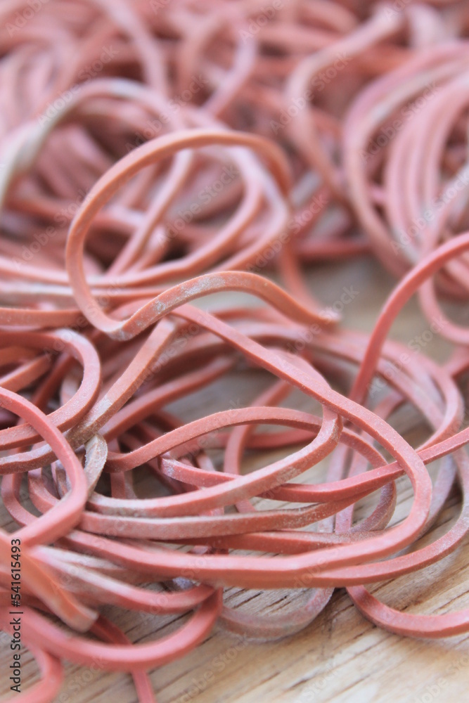 A pile of old red rubber bands on a wooden table portrait