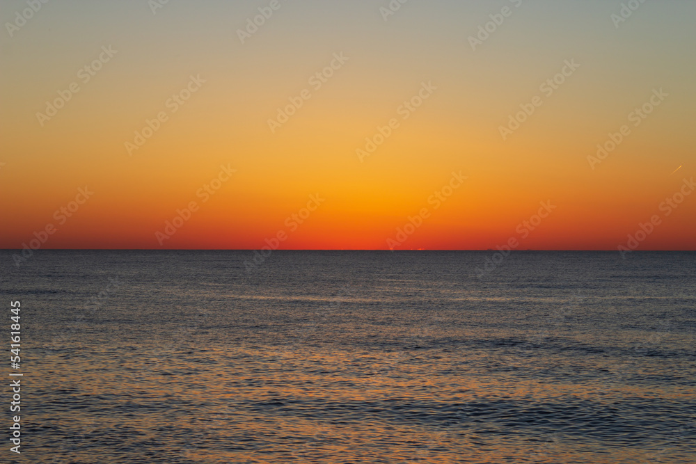 Beautiful sky with dark orange color after sunset over the sea. Georgia. Kobuleti