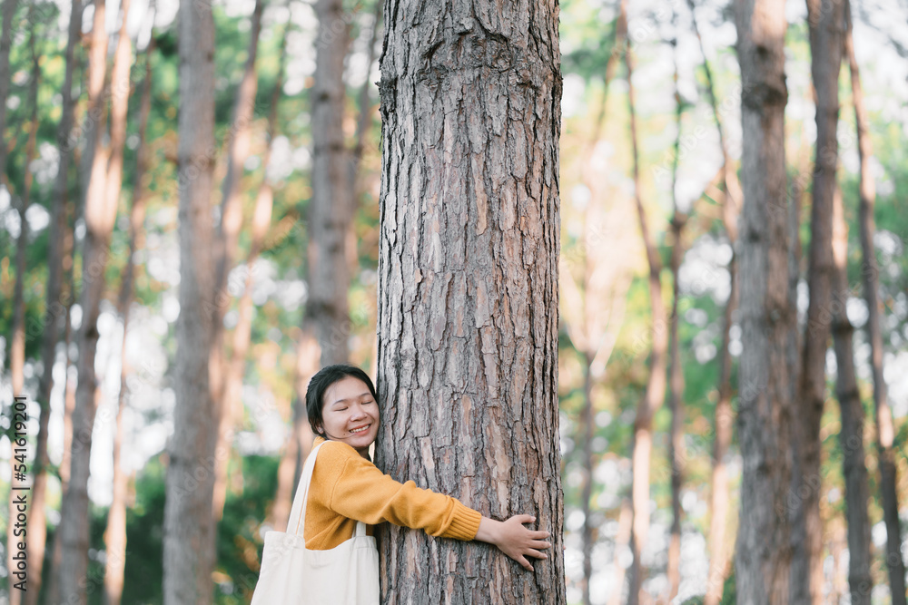 New generation young woman and the big tree in the forest. The environment is of connection sustainable development. renewable energy is environmentally friendly. Technology and new forward. New generation young woman and the big tree in the forest. The environment is of connection sustainable development. renewable energy is environmentally friendly. Technology and new forward.