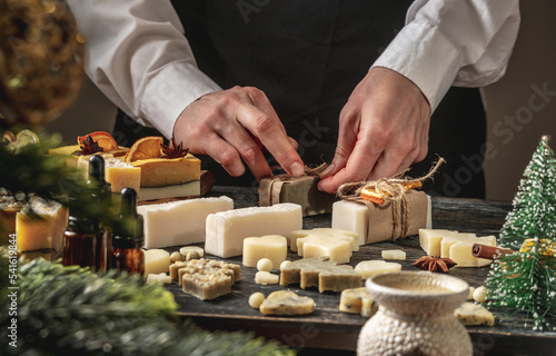 Woman is packing handmade natural soap as a gift for New Year and Christmas. Concept of preparing for holidays, hobbies, a cozy festive atmosphere