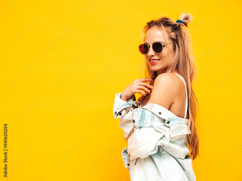 Portrait of young beautiful smiling blond female in trendy summer clothes. carefree woman posing near yellow wall in studio. Positive model having fun indoors. Cheerful and happy