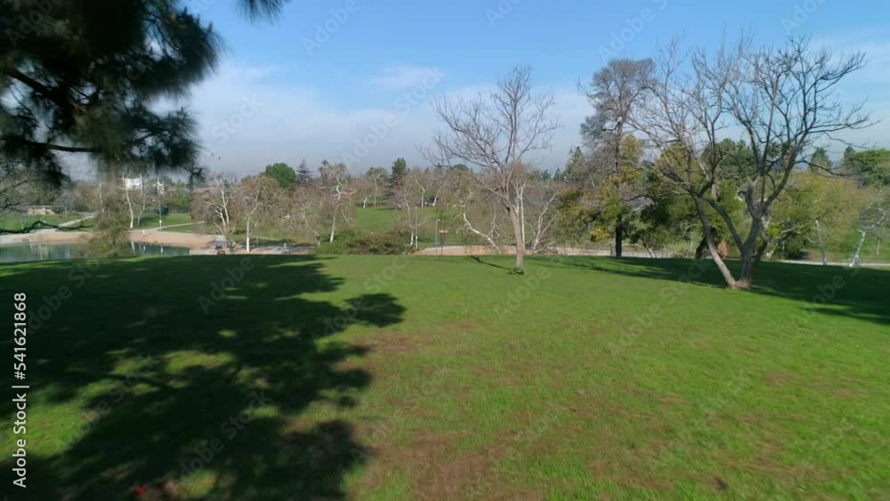 Aerial: Man Standing By Rsm Lake In Park, Drone Flying Backwards Over Green Landscape - Los Angeles, California Aerial: Man Standing By Rsm Lake In Park, Drone Flying Backwards Over Green Landscape - Los Angeles, California