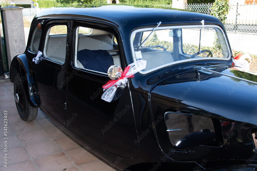 decorative ribbon hanging on vintage door of ancient bride black car at wedding day