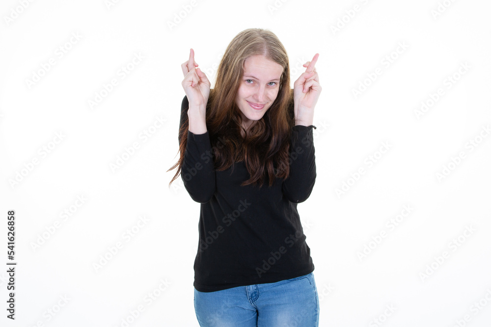 pretty young woman with her fingers crossed and her head tucked into her shoulders on white background pretty young woman with her fingers crossed and her head tucked into her shoulders on white background