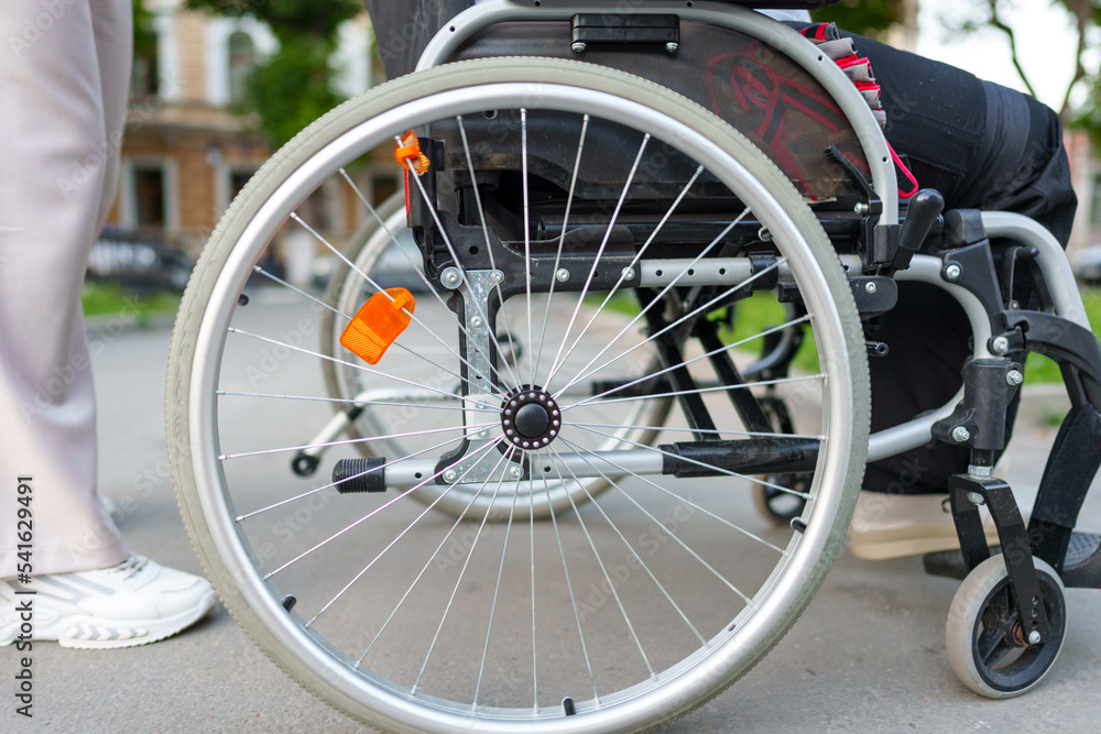 Unrecognizable woman with disability sitting in wheelchair in the street close up