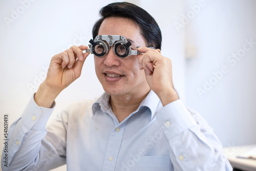 Asian man with optometrist trial frame, male patient to check vision in ophthalmological clinic