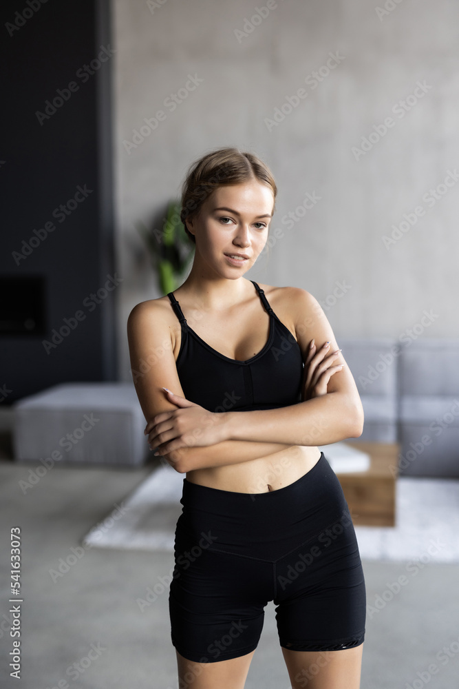 Fitness woman exercising and stretching arms at home in the living room in sportswear.