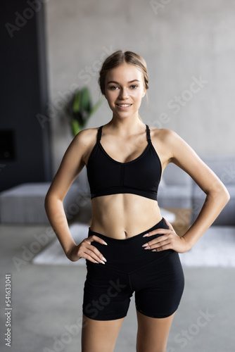 Portrait of an attractive woman wearing sportswear holding a yoga or fitness mat after working out at home.