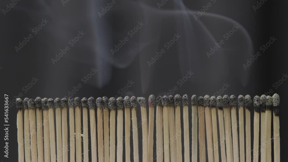 Rows of matches burning with flames close-up. View of the matches as they burn and smoke. Shot of igniting matches against black Background. Rows of matches burning with flames close-up. View of the matches as they burn and smoke. Shot of igniting matches against black Background.