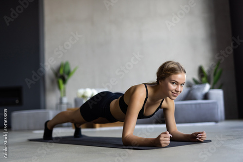 Slim fitness young woman doing plank exercise at home concept training workout crossfit gymnastics cross fit.