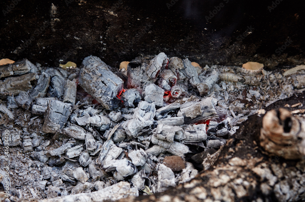 Smoldering charcoal in a barbecue. Scattered pieces of embers in the hearth mixed with ash. Ashes after to prepare food outdoor Smoldering charcoal in a barbecue. Scattered pieces of embers in the hearth mixed with ash. Ashes after to prepare food outdoor