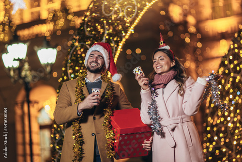Young romantic couple holding gift box having fun outdoors in winter before Christmas.