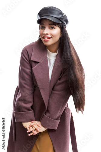Smiling young girl in an elegant wine-colored autumn coat and a black leather cap. Pretty brunette with long hair. Comfortable walks in the cold season. Isolated on a white background. Vertical.