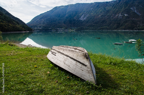 Una barca capovolta sulla riva erbosa del lago di Santa Croce in Alpago in una giornata di sole