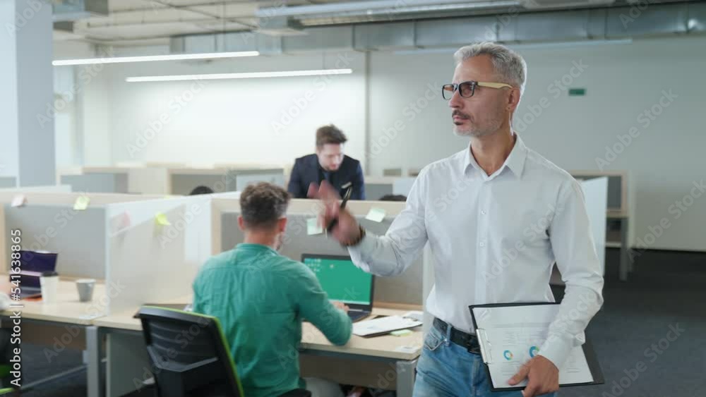 International management team at work in a open space, the project director walks around the office and communicates with colleagues. International management team at work in a open space, the project director walks around the office and communicates with colleagues.