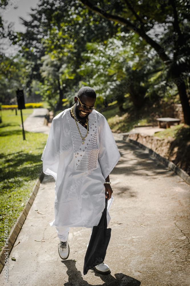 an african man in an agbada taking a walk in the park an african man in an agbada taking a walk in the park