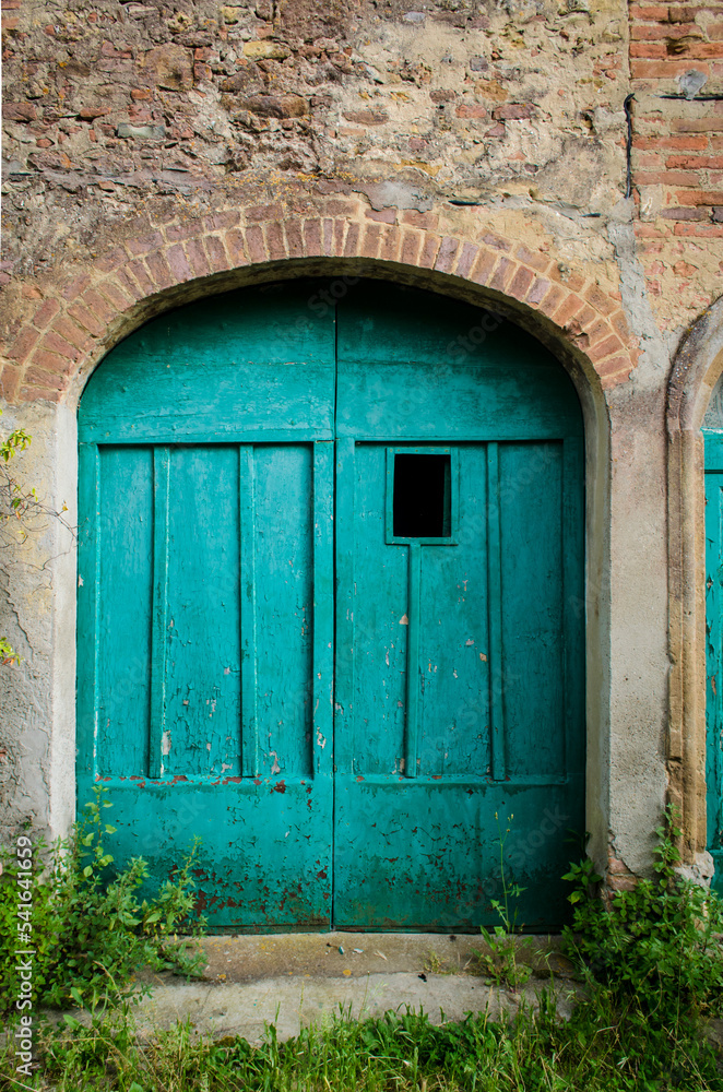 Fototapeta premium Il vecchio portone di legno dipinto in azzurro di una casa abbandonata a Toiano di Palaia, borgo abbandonato in provincia di Pisa