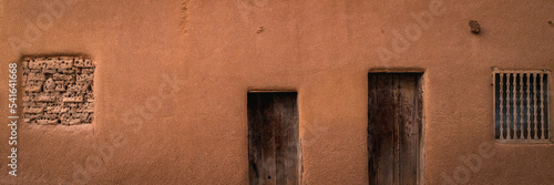 Abstract geometry of southwestern Adobe earth tone stucco wall with doors and windows 