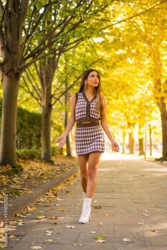 Portrait of a caucasian brunette woman in autumn, walking through a natural park in the city, autumnal lifestyle