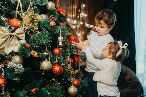 boy and girl, brother and sister are decorating a christmas tree.