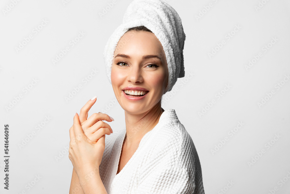 A beautiful cheerful smiling woman with perfect soft facial skin is taking care of herself with cosmetics A beautiful cheerful smiling woman with perfect soft facial skin is taking care of herself with cosmetics