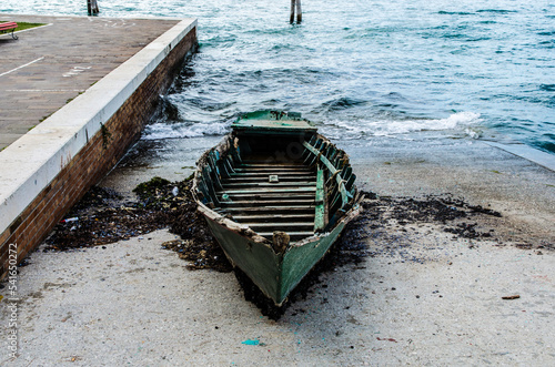 Una vecchia barca alla deriva portata a riva dalla corrente e arenata sullo scivolo di cemento dell'isola di Sant'Elena a Venezia photo