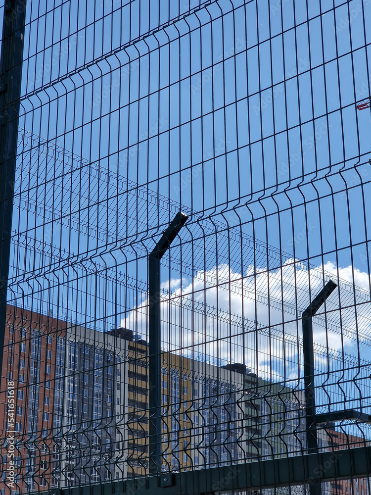 Fototapeta premium Residential building behind a mesh fence