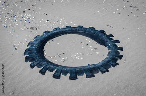 I resti di un copertone per la ruota di un camion abbandonato sulla spiaggia e sommerso dalla sabbia photo