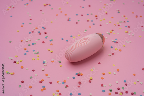 Pink sex toy vibrator on a pastel pink background with confetti photo