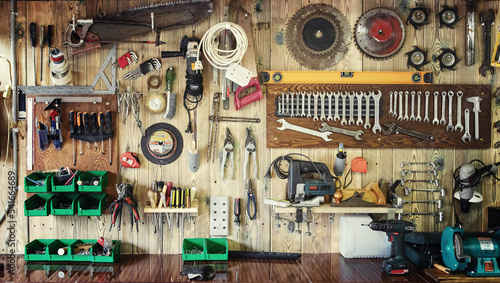 Various tools hang on a wooden wall in a workshop