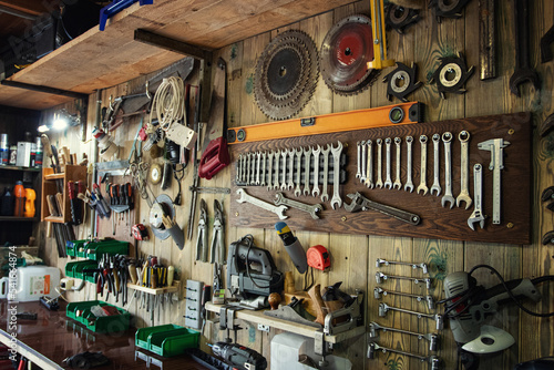 Various tools hang on a wooden wall in a workshop