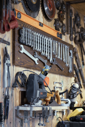 Various tools hang on a wooden wall in a workshop