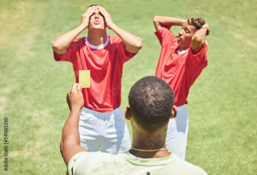 Sports, soccer and referee with yellow card standing on field with upset, angry and mad soccer players. Foul, mistake and athlete getting warning for rules violation in game or match on soccer field