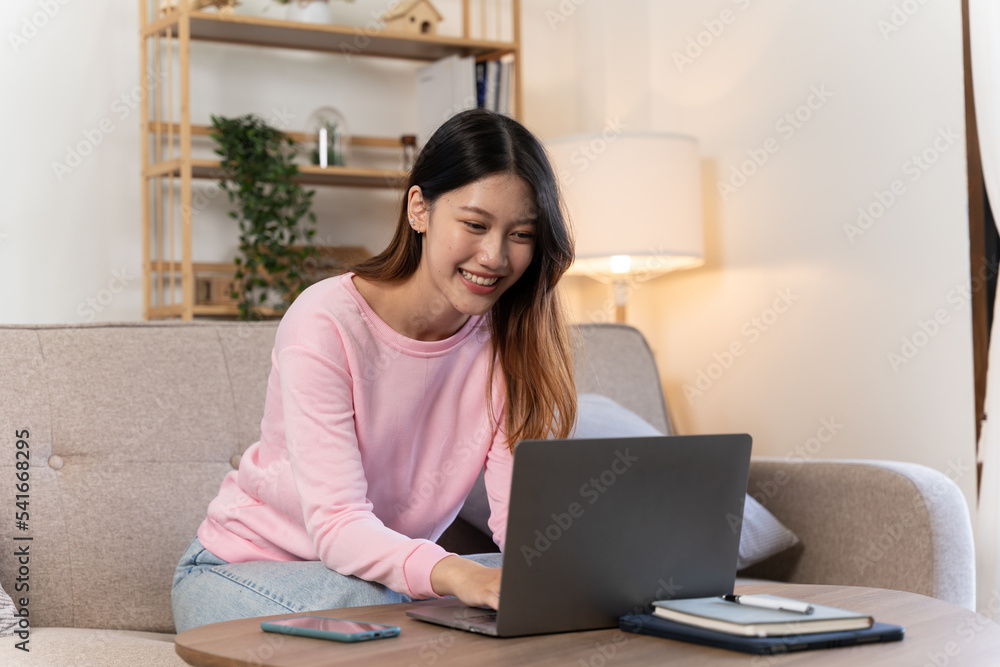 attractive smiling woman in pink shirt sitting relaxed on sofa at home at table working online on laptop from home freelancer, social distancing self isolation communication digital conference attractive smiling woman in pink shirt sitting relaxed on sofa at home at table working online on laptop from home freelancer, social distancing self isolation communication digital conference