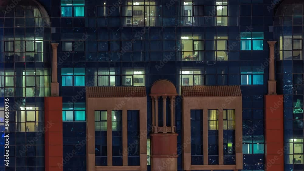 Night aerial view of apartment building glass window facade with illuminated lighted workspace rooms timelapse. Glowing light in skyscraper Night aerial view of apartment building glass window facade with illuminated lighted workspace rooms timelapse. Glowing light in skyscraper