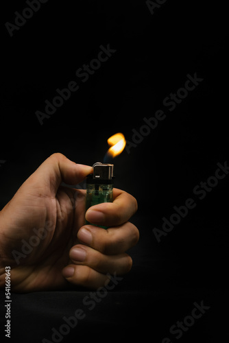 Foto Close up a lighter with a flame in a man's hand on dark background