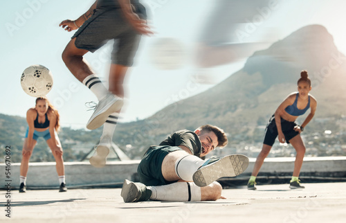 Soccer, sports and tackle with a man player sliding an opponent during a game or match on a city rooftop outdoor. Football, fitness and exercise with a soccer player slide tacking for competition